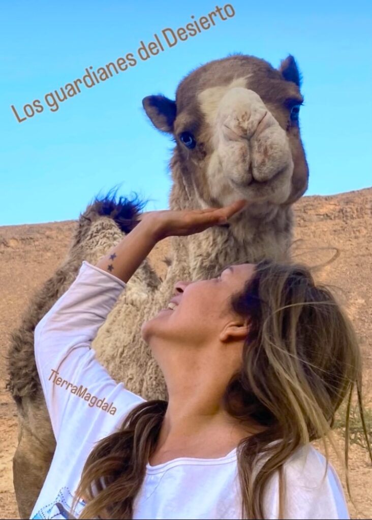 Mujer sonriente acaricia un camello en el desierto.